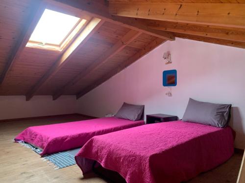 two beds in a attic room with a window at The Light Blue House in Karavostamo
