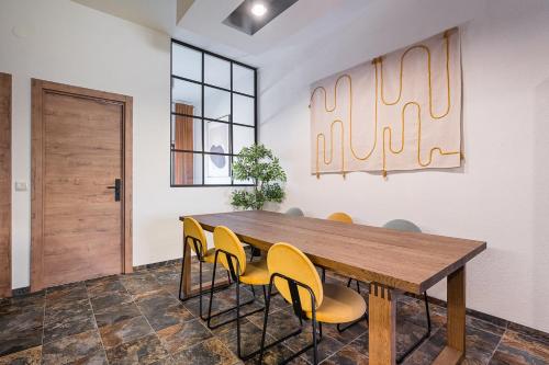 a dining room with a wooden table and yellow chairs at GuestReady - Modern Home In Gaia in Vila Nova de Gaia