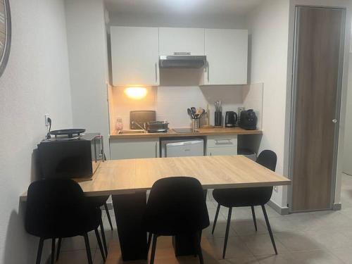 une cuisine avec une table en bois et des chaises noires dans l'établissement La Canée, à Juvignac