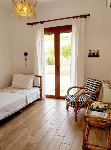 a bedroom with a bed and a chair and a sliding glass door at Villa Tsonima in Agia Marina Mikrolimanou