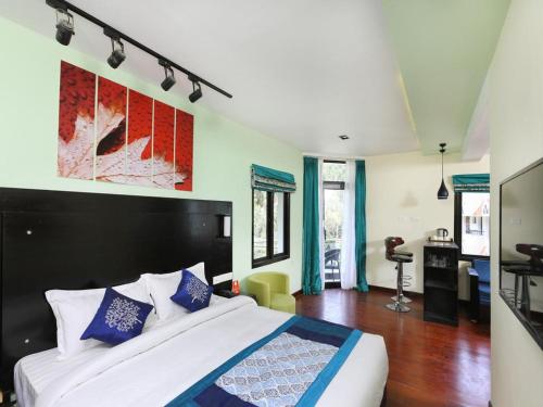 a bedroom with a large white bed with blue pillows at Infinity Destination's Kodaikanal - 0014 in Kodaikānāl