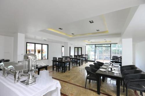 a dining room with black chairs and tables and windows at Infinity Destination's Kodaikanal - 0014 in Kodaikānāl