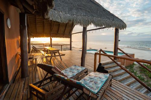 a deck with chairs and an umbrella and the ocean at Sia Sente Beach estate in Inhambane
