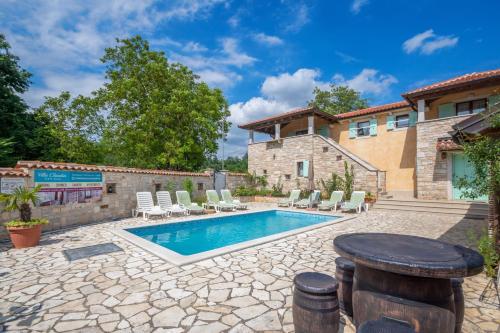 a pool with chairs and a table in front of a house at Villa Sandi, mediterranean Villa with pool and jacuzzi in Gračišće