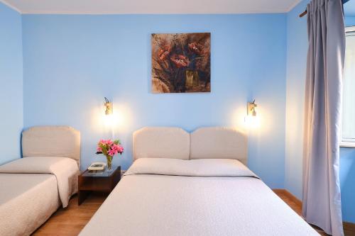a bedroom with two beds and a painting on the wall at Albergo Della Posta in Bracciano