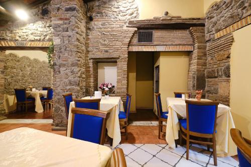 a restaurant with tables and chairs and a stone wall at Albergo Della Posta in Bracciano
