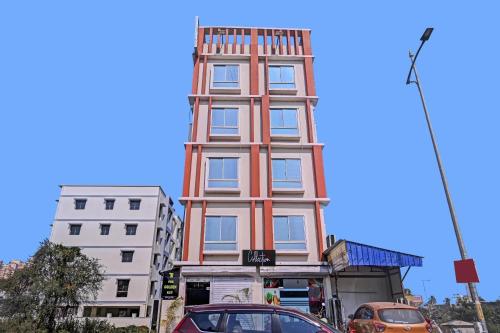 un edificio alto en una calle con coches aparcados delante en Collection O New Avro Hotel Near Eco Park en Salua