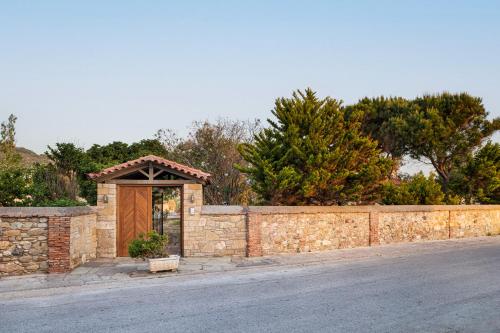 a stone wall with a wooden door and a fence at Samos Wine Factory Guesthouse Villa in Karlovasi