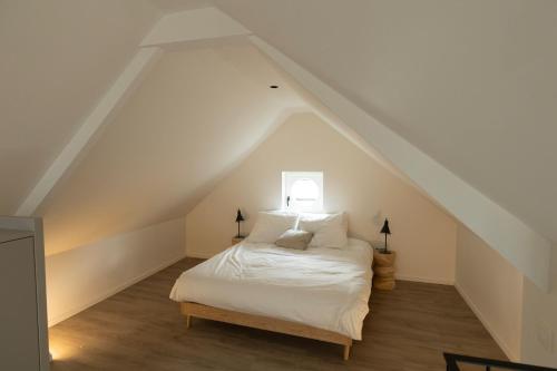 a bedroom with a white bed in a attic at Zeer unieke vakantiewoning in Herentals