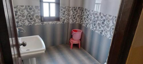 baño con lavabo y taburete rojo. en Hotel Saint, en Pālampur