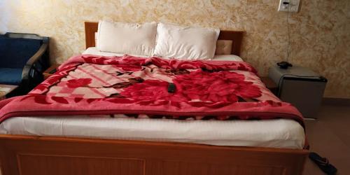 1 cama con manta roja y almohadas blancas en Hotel Saint en Pālampur