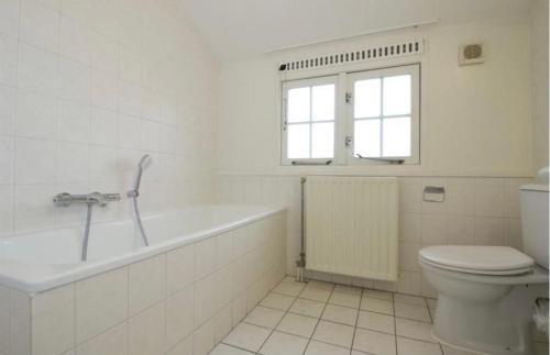 a white bathroom with a tub and a toilet at Modern Vakantiehuis op Loopafstand van de Zee in Kamperland in Kamperland