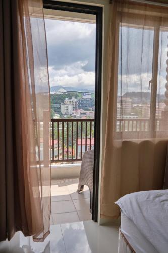 a bedroom with a window with a view of a city at QFandZ Baguio Homestay at BRENTHILL Condominium in Baguio