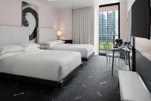 a hotel room with three beds and a desk and a television at DUA Miami, Autograph Collection in Miami