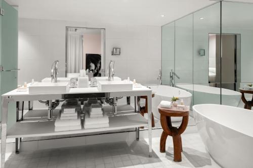 a bathroom with three sinks and a bath tub and a bath tub at DUA Miami, Autograph Collection in Miami