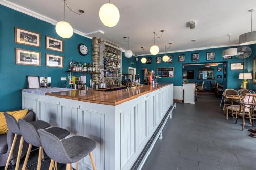 eine Bar in einem Restaurant mit blauen Wänden und Stühlen in der Unterkunft The Cornerhouse in Frome