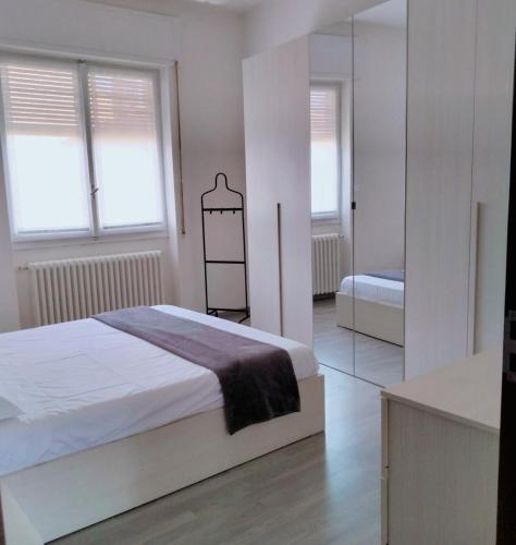 a white bedroom with a bed and a mirror at DOBA House in Baveno