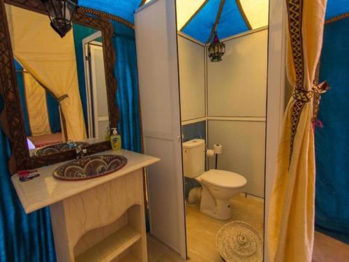 a bathroom with a toilet and a sink and a mirror at Yellow Luxury Camp in Merzouga