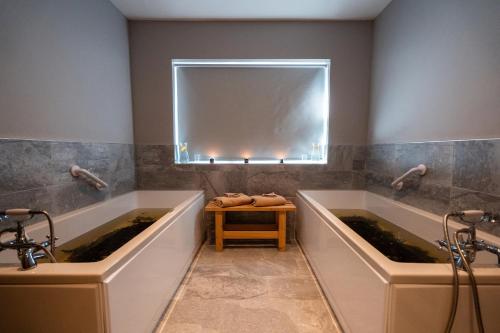 two bath tubs in a bathroom with a mirror at Seaview House Hotel in Bantry