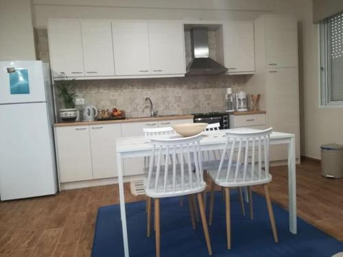 a kitchen with white cabinets and a white table and chairs at Garden in Almirón