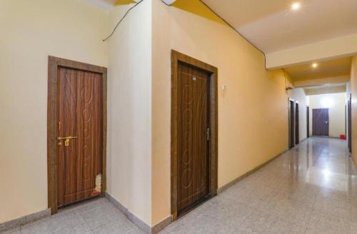 pasillo con 2 puertas marrones y suelo de baldosa en Gsv hotel, en Kānpur