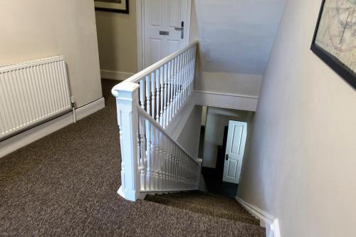 a staircase with white railings and a white door at The Cornerhouse in Frome