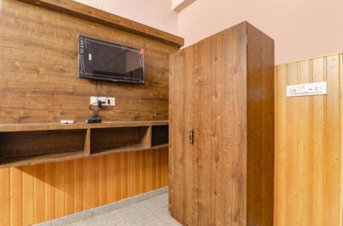 een kamer met een tv aan een houten muur bij Gsv hotel in Kānpur