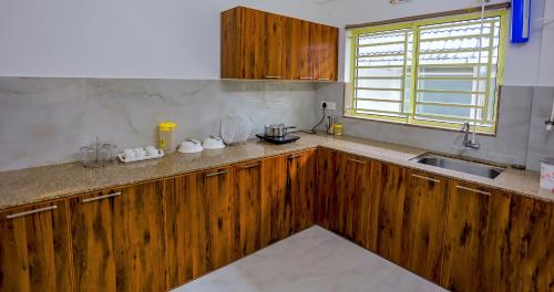 a kitchen with wooden cabinets and a sink and a window at BHRS Residency in Munnar