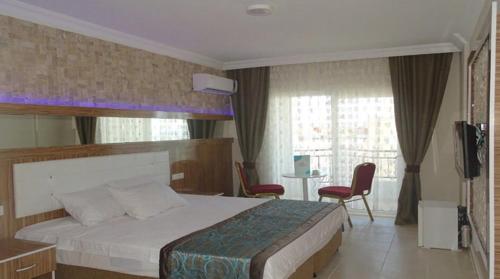 sypialnia z łóżkiem, 2 krzesłami i telewizorem w obiekcie PRİNCESS AQUA RESORT & SPA w mieście Beyreli