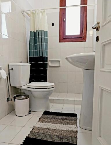 a white bathroom with a toilet and a sink at Villa Tsonima in Agia Marina Mikrolimanou