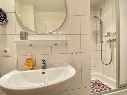 ein Bad mit einem Waschbecken, einem Spiegel und einer Dusche in der Unterkunft Haus Inge in Heringsdorf