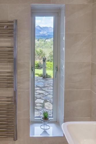 a bathroom with a tub and a window with a plant at Patch House Glengarriff in Glengarriff