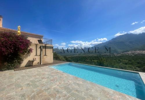 une villa avec une piscine et des montagnes en arrière-plan dans l'établissement Villa ALTORE, à Calenzana