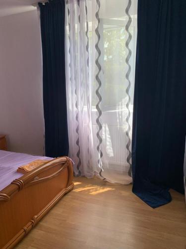 1 dormitorio con 1 cama y una ventana con cortinas en Apartament închiriere, en Târgovişte