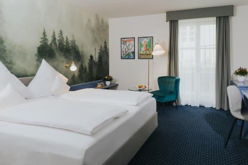 a hotel room with a white bed and a green chair at Gutshof Sagmühle in Bad Griesbach