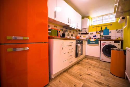 eine orangefarbene und weiße Küche mit Waschmaschine und Trockner in der Unterkunft Luxurious quirky flat in Greenwich O2 Arena with free parking in London