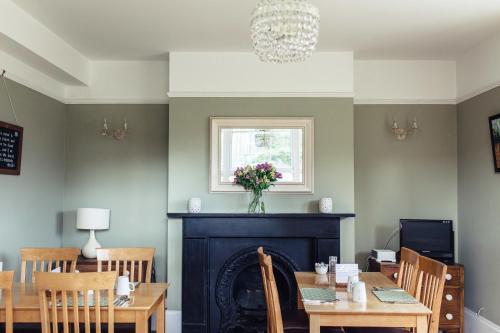 a dining room with a fireplace and a table and chairs at The Caledon Guest House in Cowes