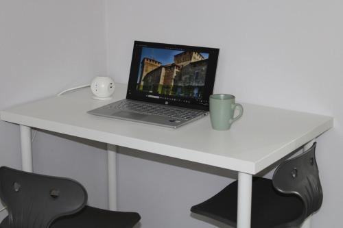 a laptop computer sitting on a white desk with a cup at la Luna Blu Malpensa camera matrimoniale Diamante in Somma Lombardo