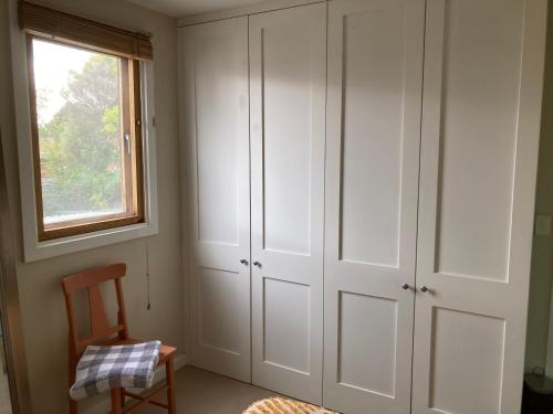 sypialnia z białymi szafkami i oknem w obiekcie Preston Accommodation- beautiful quiet room w Melbourne