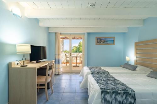a hotel room with a bed and a desk with a computer at Cala Della Torre Resort in La Caletta