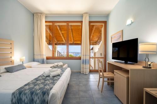 a hotel room with two beds and a flat screen tv at Cala Della Torre Resort in La Caletta