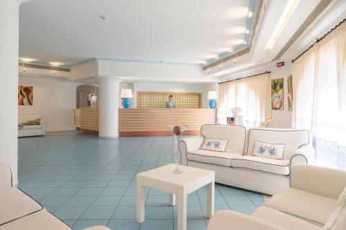 a living room with two white couches and a table at Cala Della Torre Resort in La Caletta