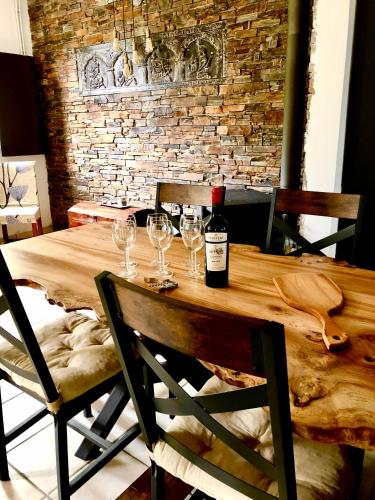 - une table en bois avec une bouteille de vin et des verres dans l'établissement Bienvenu chez Nathalie, à Châtillon