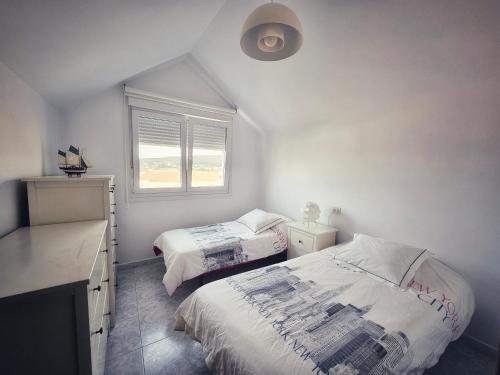 a bedroom with two beds and a window at Casa del Arenal - Laxe in Laxe