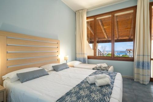 a bedroom with two beds and a large window at Cala Della Torre Resort in La Caletta