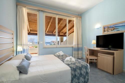 a bedroom with a bed and a desk and a television at Cala Della Torre Resort in La Caletta