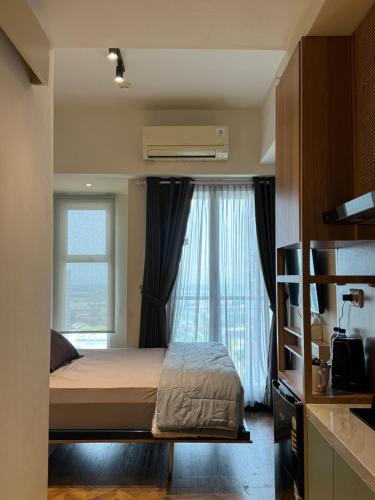 a bedroom with a bed and a large window at Studio Amor Apartemen Pakuwon City Mall in Surabaya