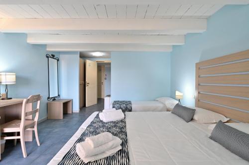 a room with a bed and a desk and a couch at Cala Della Torre Resort in La Caletta