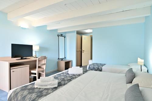 a bedroom with a bed and a desk with a television at Cala Della Torre Resort in La Caletta