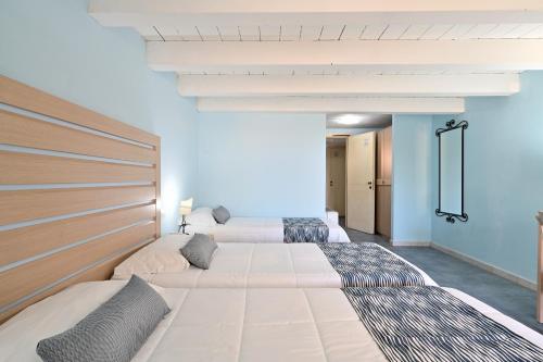 two beds in a room with blue walls at Cala Della Torre Resort in La Caletta